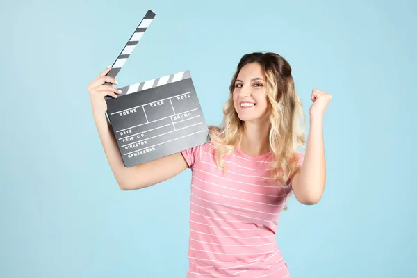 Mujer joven con tablero de aplausos en blanco sobre fondo azul —  Fotos de Stock