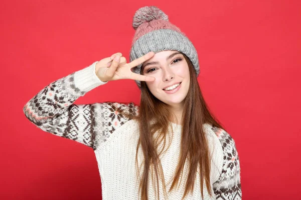 美しい女性でセーターと帽子で赤い背景 — ストック写真