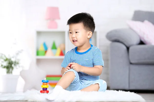 Vacker pojke sitter och leker med Rainbow Toy hemma — Stockfoto