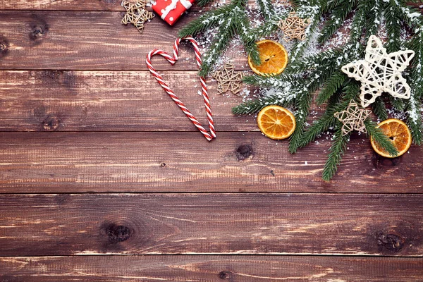 Kerstboomtakken met sinaasappelvruchten en snoepjes op bruin — Stockfoto