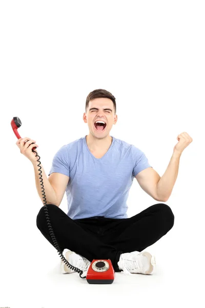 Junger Mann mit Hörer sitzt und schreit auf weißem Hintergrund — Stockfoto