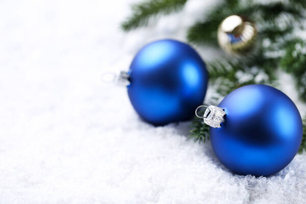 Christmas baubles with fir tree branches on white snow