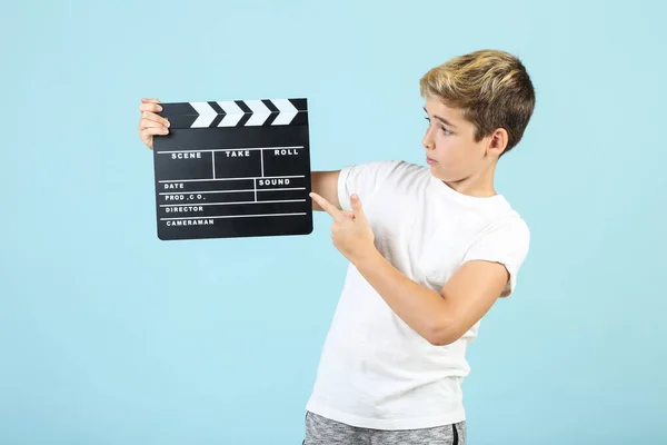 Young boy with clapper board on blue background — Stock Photo, Image