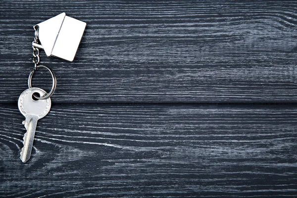 Zilveren sleutel met huis symbool op zwarte houten tafel — Stockfoto