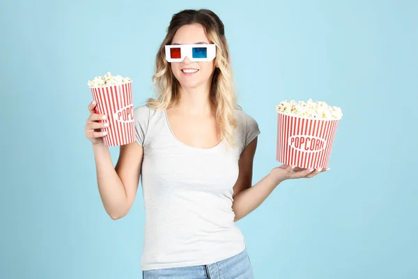 Junge Frau in Gläsern mit Eimern mit Popcorn auf blauem Rücken — Stockfoto