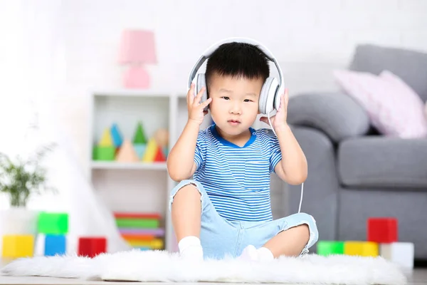 Piękny chłopiec ze słuchawkami siedzi w domu — Zdjęcie stockowe