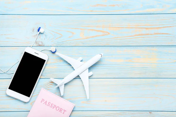 Pasaportu, akıllı telefonu ve kulaklığı mavi olan uçak modeli. — Stok fotoğraf