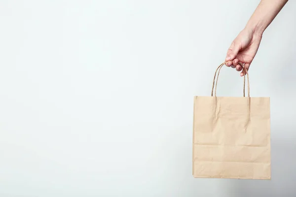 Weibliche Hand hält Einkaufstasche auf grauem Hintergrund — Stockfoto
