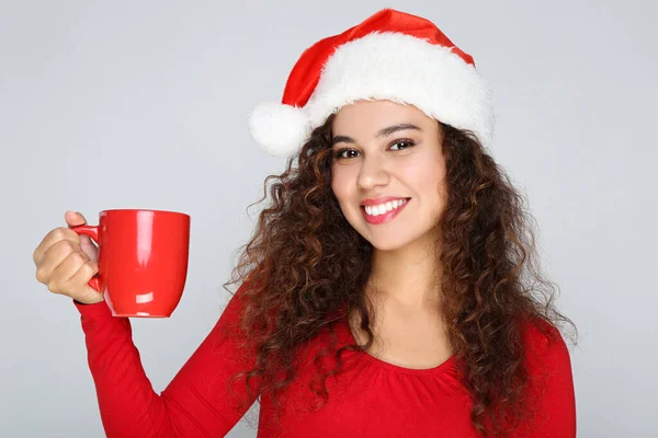 Vacker amerikansk kvinna bär tomte hatt och hålla kopp te — Stockfoto