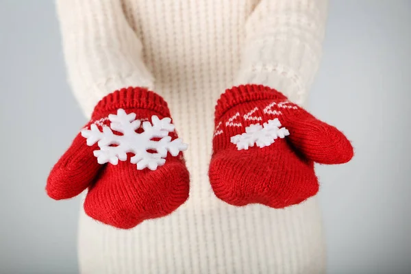 Hands in knitted mittens holding snowflakes on grey background — Stock Photo, Image