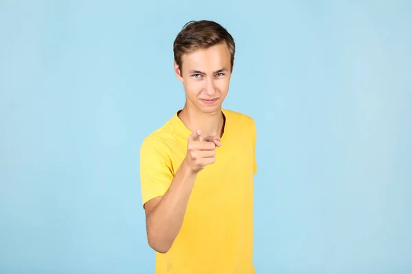 Porträtt av ung man i gul t-shirt på blå bakgrund — Stockfoto