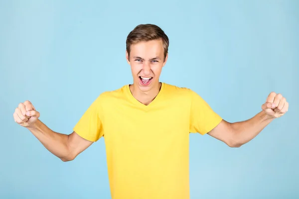Portret van de jonge man in geel t-shirt op blauwe achtergrond — Stockfoto