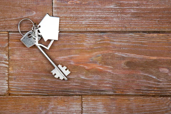 Kunci perak dengan simbol rumah di atas meja kayu cokelat — Stok Foto