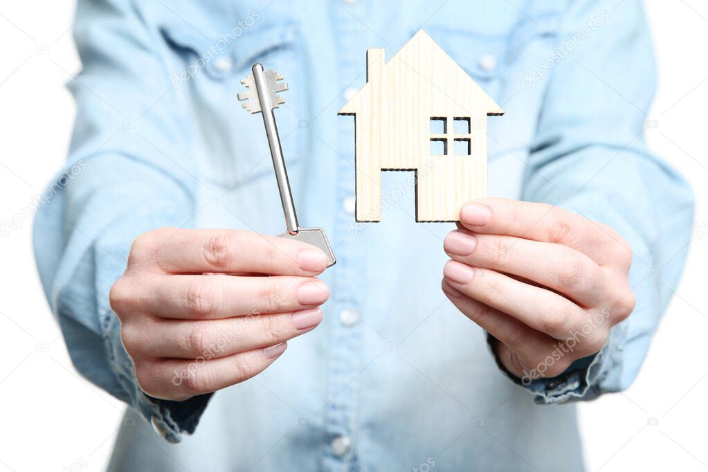 Female hand holding silver key and wooden house