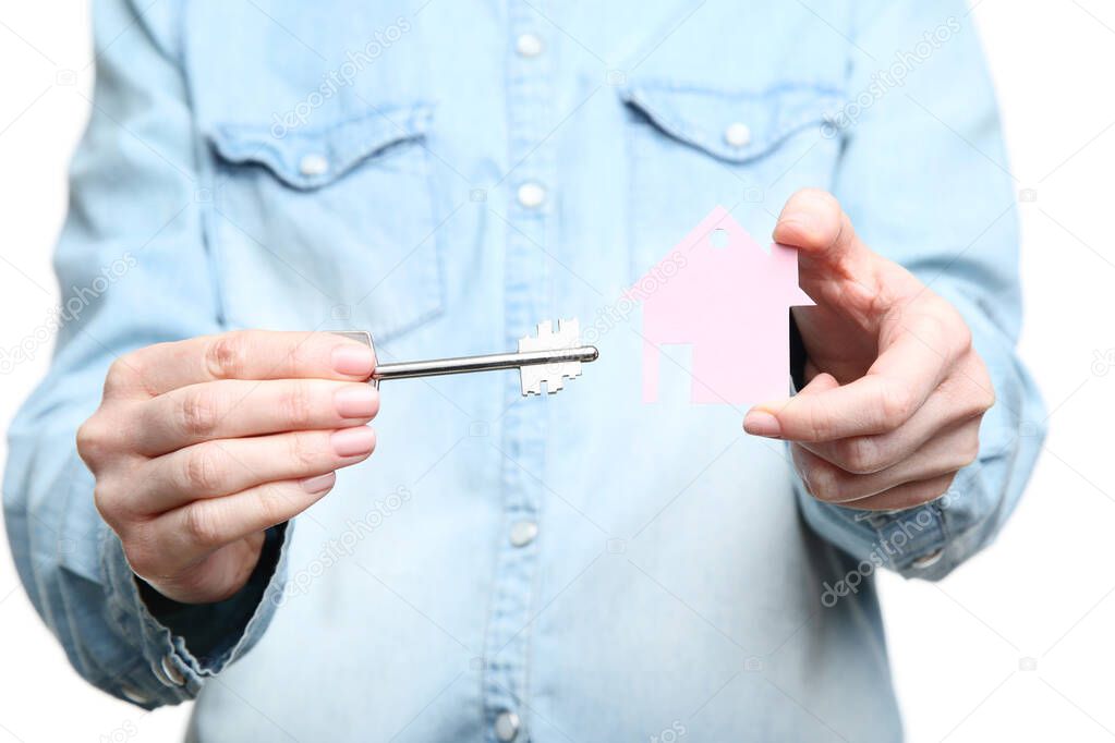 Female hand holding silver key with pink paper house