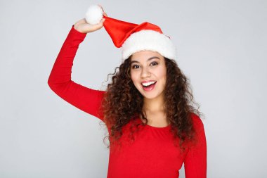 Gri arka planda Noel Baba şapkalı güzel bir Amerikalı kadın.