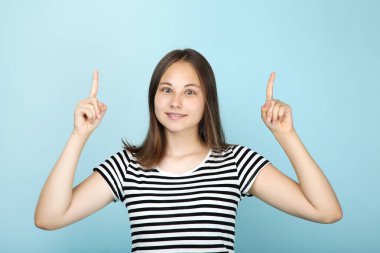 Mavi arka planda iki parmağını gösteren güzel bir kız.