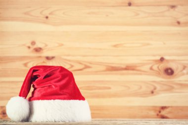 Kahverengi ahşap arka planda kırmızı Noel Baba şapkası