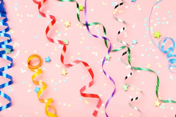 Kolorowe wstążki konfetti i gwiazdy papieru na różowym tle — Zdjęcie stockowe