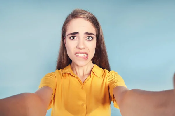 Ung känslomässig flicka gör selfie på blå bakgrund — Stockfoto