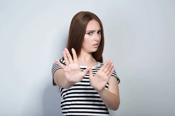 Ung kvinna i randig t-shirt på grå bakgrund — Stockfoto