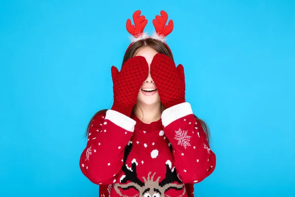 Mooie vrouw in kerst trui, handschoenen en rode horens op blauwe achtergrond — Stockfoto