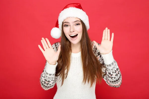 Beautiful woman in sweater and santa hat on red background — Stock Photo, Image