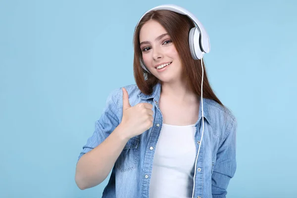 Jonge mooie vrouw met koptelefoon op blauwe achtergrond — Stockfoto