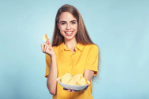 Молодая красивая девушка с картофельными чипсами в миске на синей спинке — стоковое фото