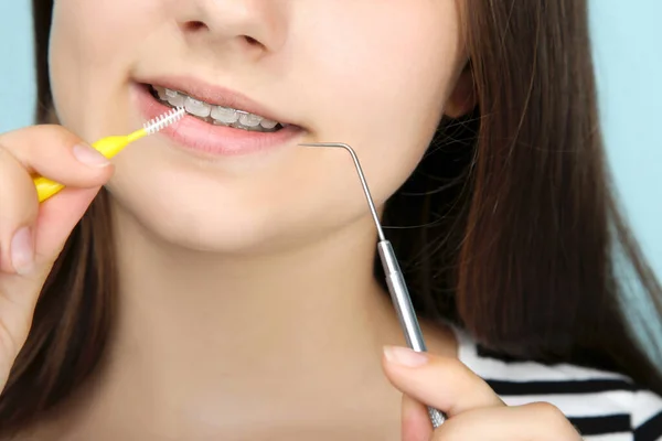 Νεαρή κοπέλα με οδοντικά σιδεράκια που κρατάει οδοντόβουρτσα και οδοντίατρο — Φωτογραφία Αρχείου
