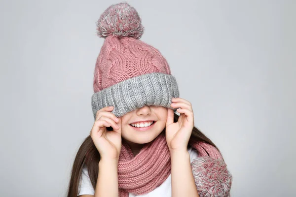 Little girl in hat and scarf on grey background — Stock Photo, Image