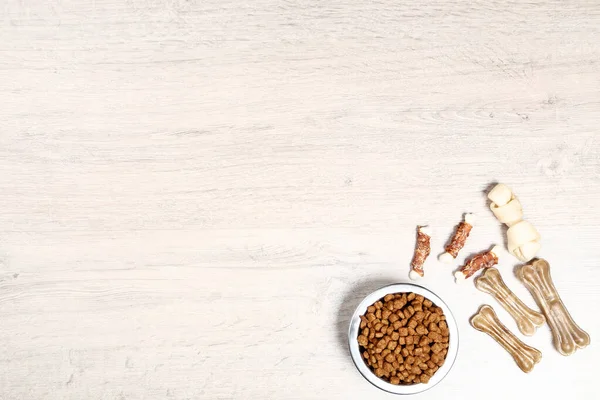 Nourriture sèche pour animaux de compagnie dans un bol avec des os sur le sol — Photo
