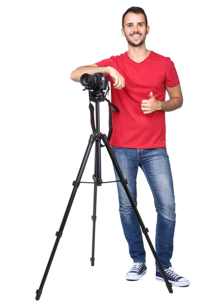 Młody fotograf pokazuje kciuk do góry kamerą na statywie izolat — Zdjęcie stockowe