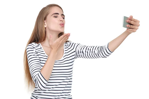 Молодая красивая девушка посылает поцелуй и делает селфи на смартфоне — стоковое фото