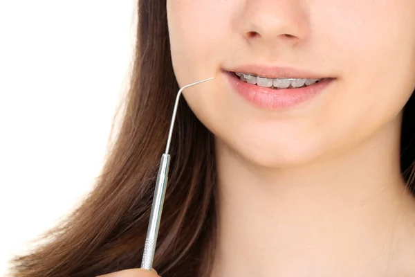 Menina com aparelho dentário segurando ferramenta dentista na parte traseira branca — Fotografia de Stock