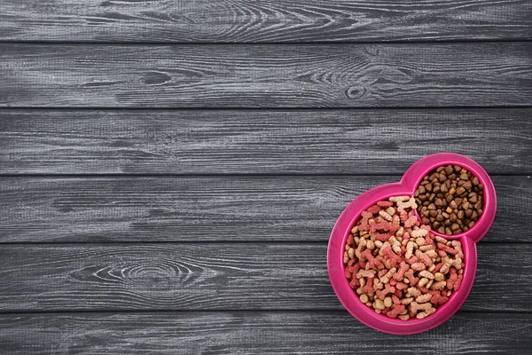Nourriture sèche pour animaux dans un bol sur une table en bois noir — Photo