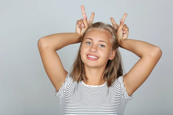 Retrato de una joven mostrando orejas por las manos sobre fondo gris — Foto de Stock