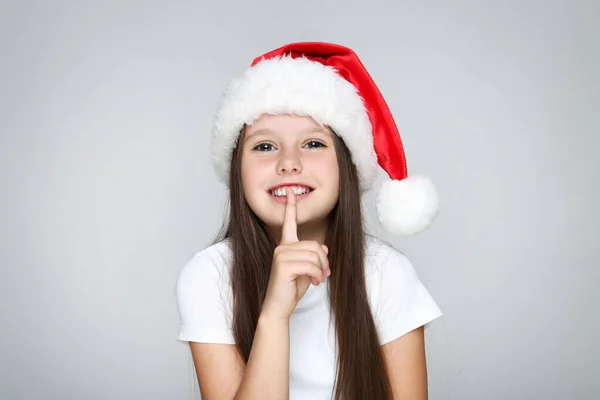 Klein meisje in kerst hoed op grijze achtergrond — Stockfoto