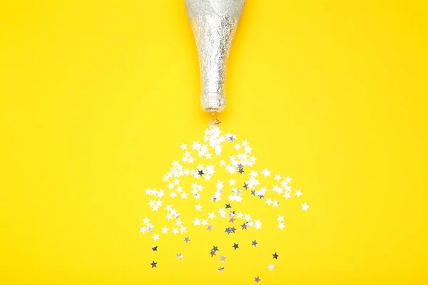 Срібні зірки з пляшкою шампанського на жовтому фоні — стокове фото
