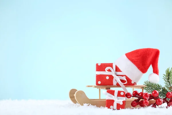 Chapeau santa rouge avec coffrets cadeaux, baies rouges et traîneau en bois sur — Photo