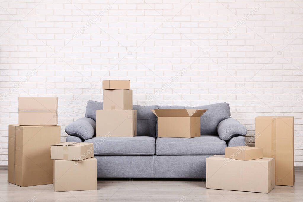 Cardboard boxes with grey sofa on brick wall background
