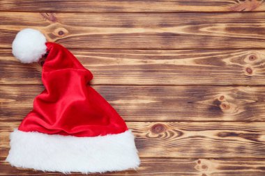 Kahverengi ahşap masada kırmızı Noel Baba şapkası