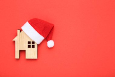 Kırmızı arka planda ev modeli olan Noel Baba şapkası