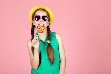 Pembe arka planda tatlı lolipop ile güzel genç kız