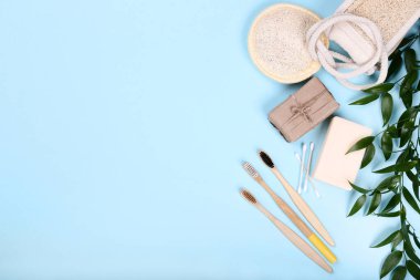 Sabun, bez ve mavi arka planda yeşil yapraklı bambu diş fırçaları.