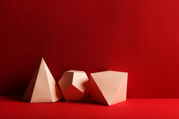 Паперові геометричні фігури на червоному тлі — стокове фото