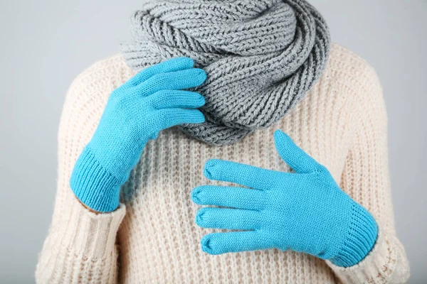 Woman wearing blue knitted mittens, grey scarf and pullover on g