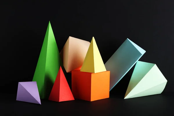 Figuras geométricas de papel de colores sobre fondo negro —  Fotos de Stock