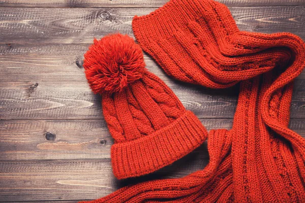 Gorro y bufanda de punto sobre mesa de madera marrón —  Fotos de Stock