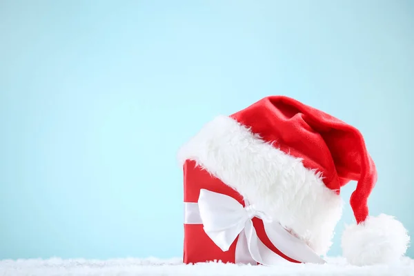 Sombrero rojo de santa con caja de regalo sobre fondo azul — Foto de Stock